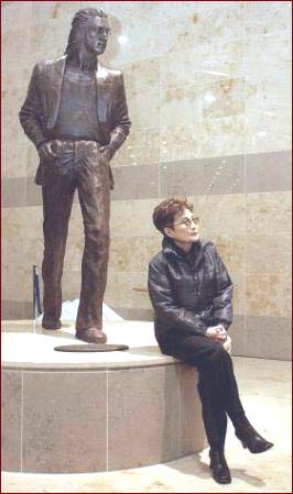 Yoko Ono sits in front of the John Lennon statue at the John Lennon Liverpool Airport.